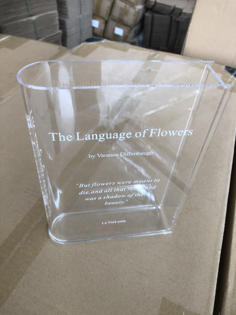 Transparent book vase shown with flowers